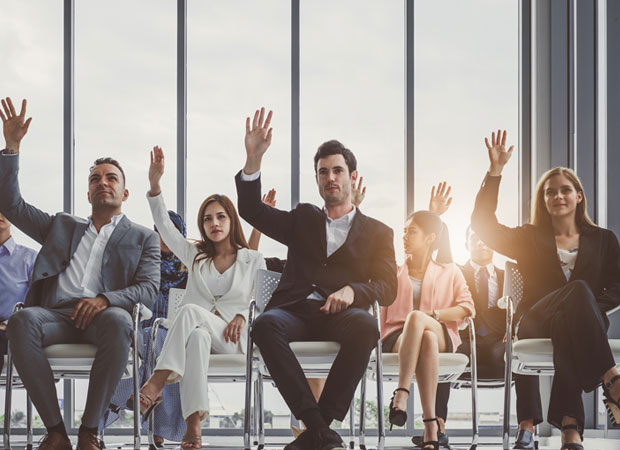 Working professionals raising hand during corporate ed training