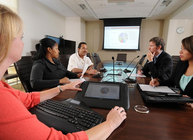 Working professionals gather around conference table during meeting