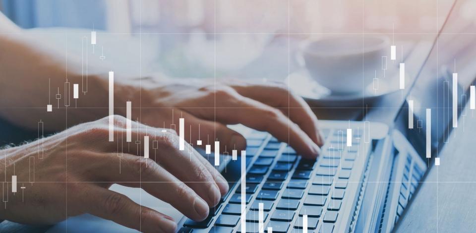 Fintech concept of candlestick chart about finance and trading quotations overlayed on laptop.