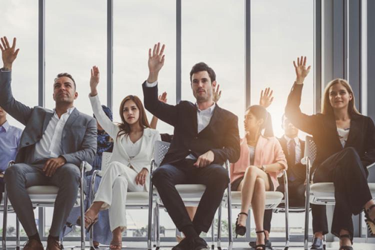 Working professionals raising hand during corporate ed training