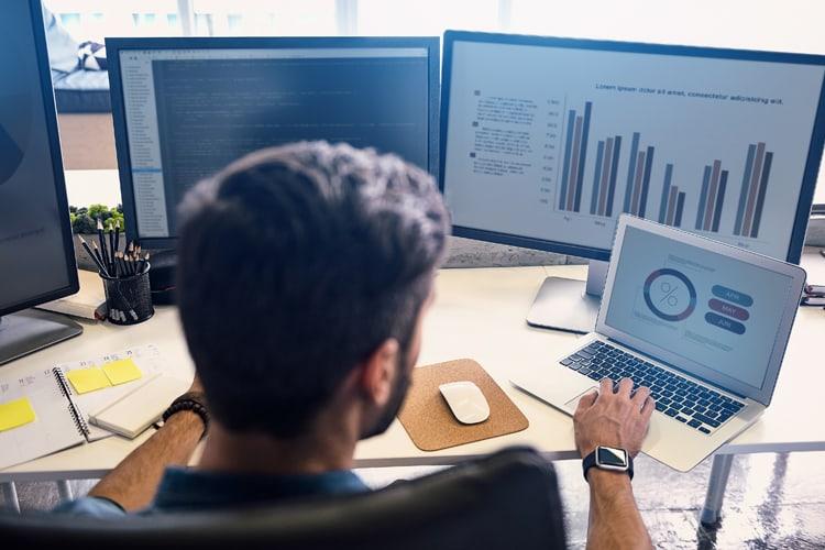 Analytics professional working on two desktop monitors