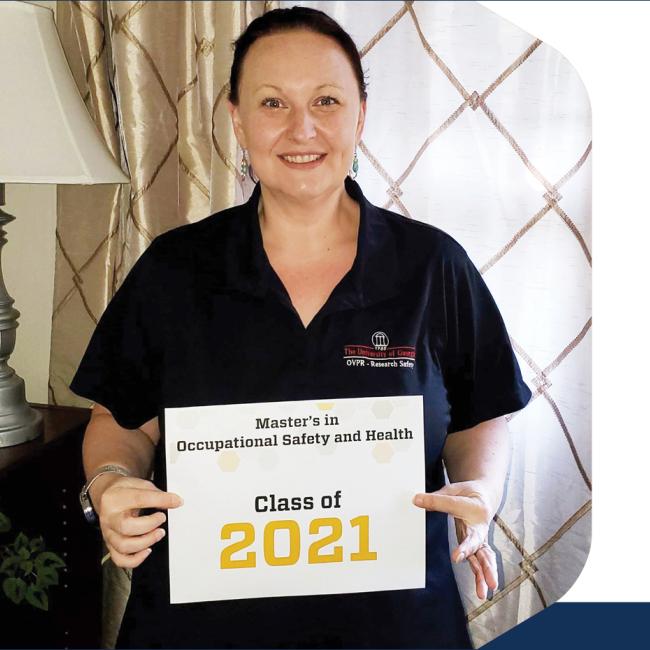 Cara Eck, industry hygienist, stands with her Professional Master's in Occupational Safety and Health Class of 2021 sign.