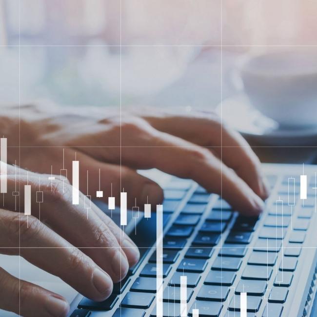 Fintech concept of candlestick chart about finance and trading quotations overlayed on laptop.