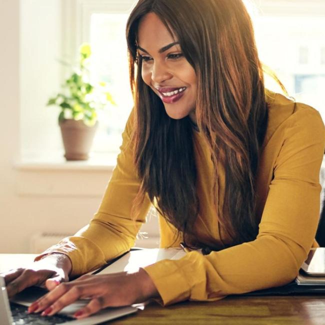 A person in a yellow shirt typing on a computer